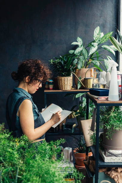 istock Florist Writing Notes about Plants at her Shop 1225272928