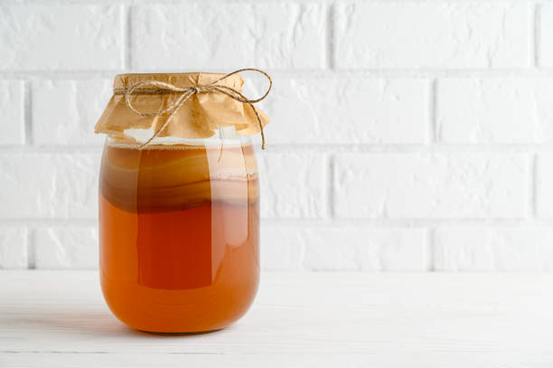 Homemade fermented kombucha tea in a glass jar on a background of a white brick wall. stock photo