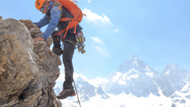 Mountaineer climbs up mountain face Sunny scene of mountain ranges in distance upward mobility stock pictures, royalty-free photos & images