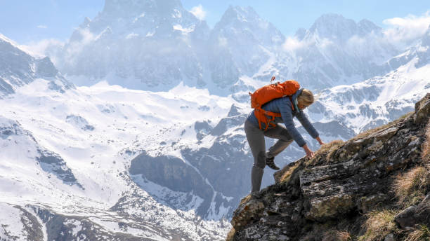 istock Female hiker scrambles up mountain ridge 1225279212
