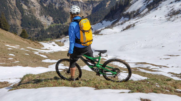 istock Mountain biker prepares to ride down snowy mountain ridge 1225280185