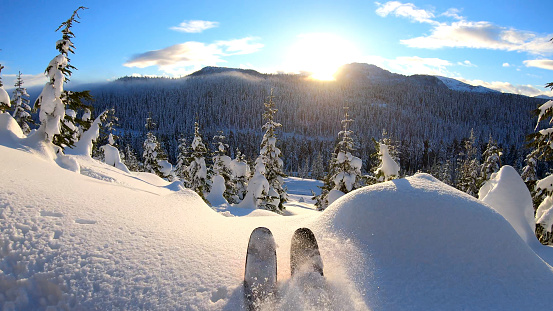 POV of backcountry skier riding through fresh powder snow at sunrise