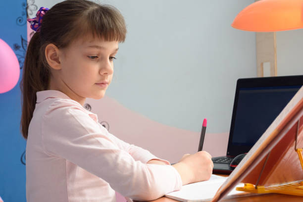 istock Girl does a job from a textbook at home sitting at a table 1225282047