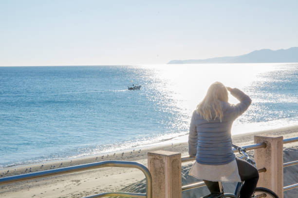 istock Female cyclist relaxes by mediterranean coastline 1225285325