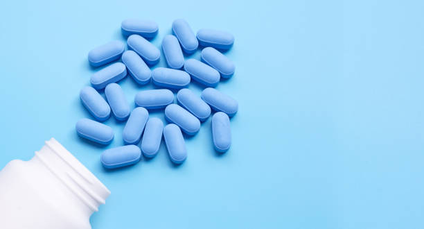 istock Medical blue pills with white plastic bottle on blue background. 1225287026