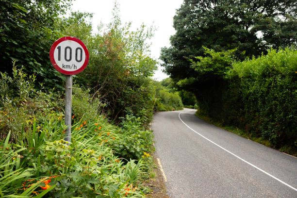 Speed limit sign on narrow Irish country road of 100 kilometres per hour A 100 kilometer per hour traffic sign on a narrow country road in Ireland 100 mph stock pictures, royalty-free photos & images