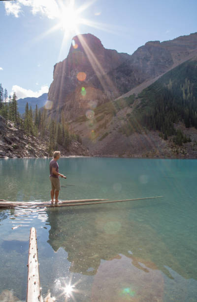 istock Man balances on logs submerged in alpine lake 1225294422