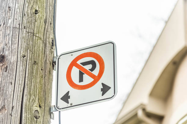 A no parking sign against a house and sky.