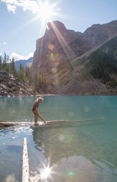 istock Man balances on logs submerged in alpine lake 1225295040