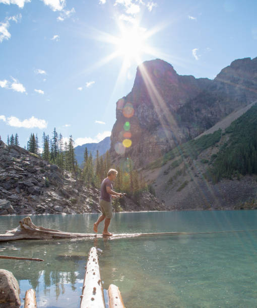 istock Man balances on logs submerged in alpine lake 1225295120