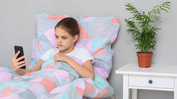 istock Girl communicates by video calling while lying in bed with a mobile phone 1225298466
