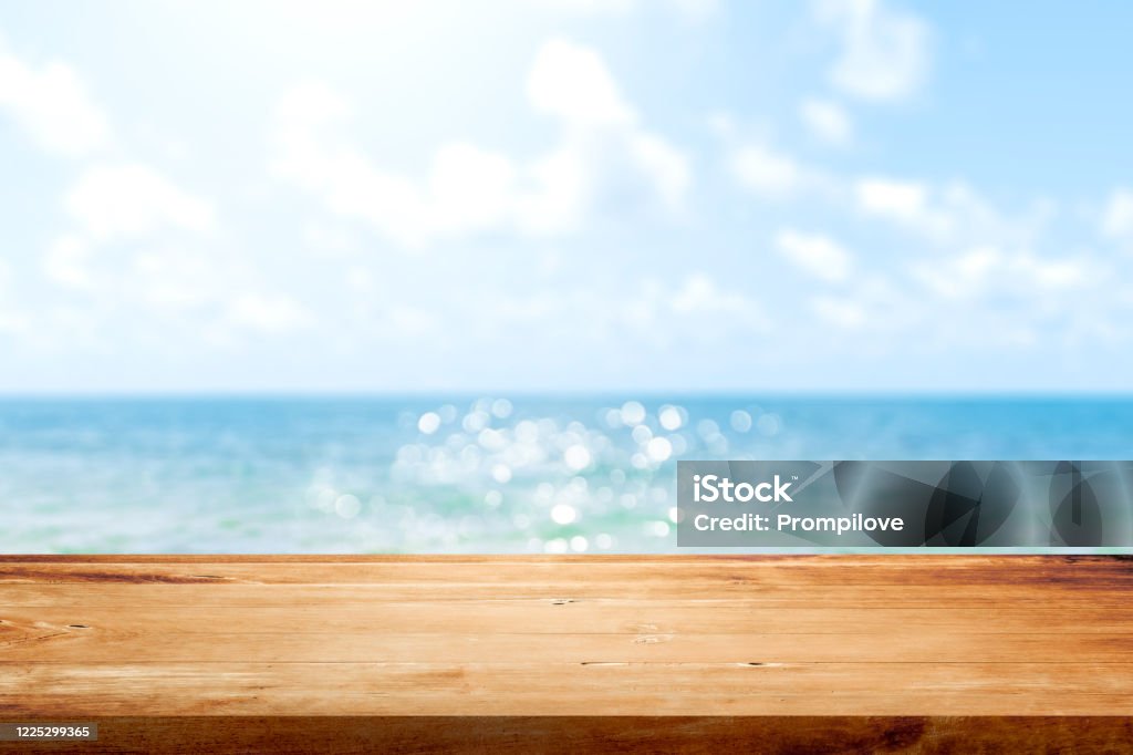 Wooden table top on blurred summer blue sea and sky background. Copy space for your display or montage product design. Summer Stock Photo
