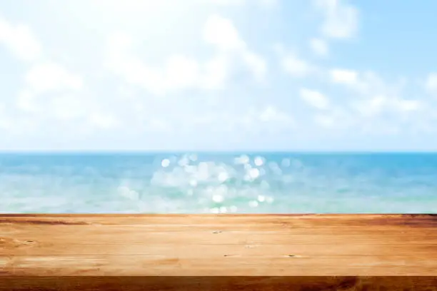 Photo of Wooden table top on blurred summer blue sea and sky background. Copy space for your display or montage product design.