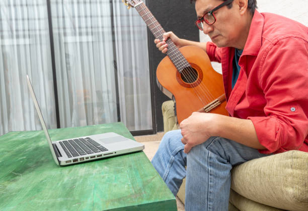 istock A man watches a video lesson on playing the guitar 1225300093