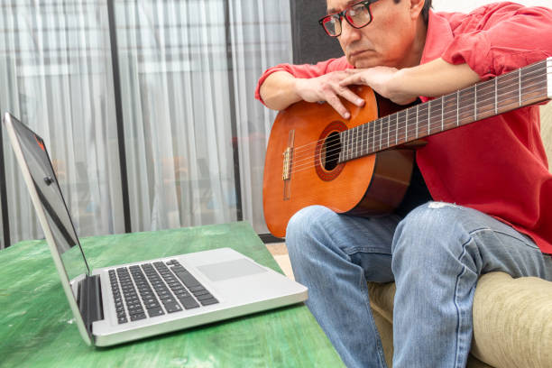 istock Man intently watches an internet guitar class 1225300096