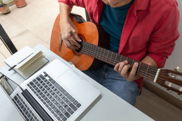 istock Man receiving online guitar lessons at home 1225300163
