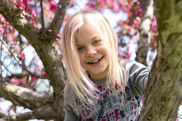 Portrait of a young blonde girl in a flowering tree