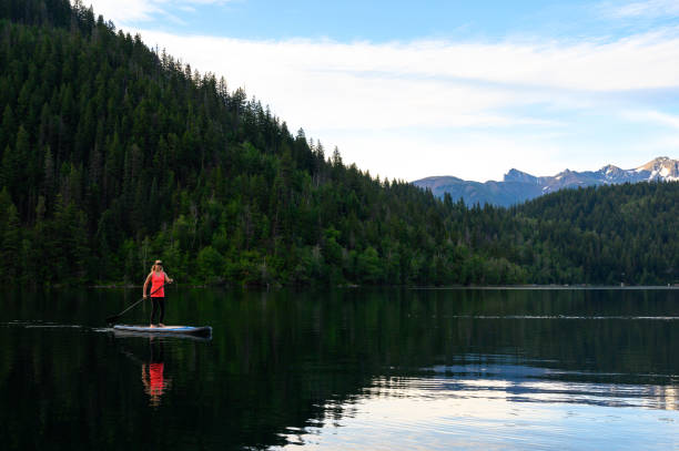 istock Woman stand up paddle boarding on a pristine mountain lake 1225302588