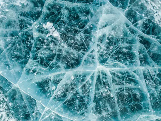 Photo of Beautiful cracks surface of the frozen lake of Baikal lake with frost methane bubbles in winter season.