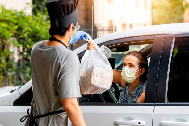 donna matura che raccoglie il cibo del suo ristorante dalla sua auto a una curva di raccolta - hat women chef occupation foto e immagini stock