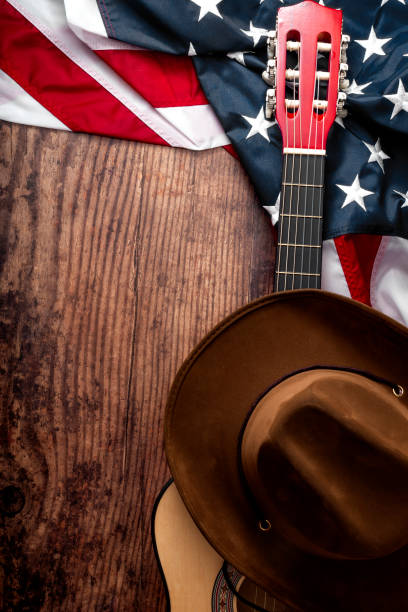 amerikanische kultur, lebend auf einer ranch und country-musik-konzept-thema mit einem cowboyhut, usa-flagge und akustikgitarre auf holzigem hintergrund in einem alten salon mit kopierraum - western theme stock-fotos und bilder