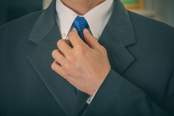 Closeup of elegant young fashion man dressing up for wedding ceremony. Groom or businessman dressed in a modern grey formal suit attire with white shirt getting ready for the evening event,