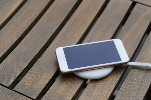 istock close up one smartphone on wireless charger on wooden table. 1225316340