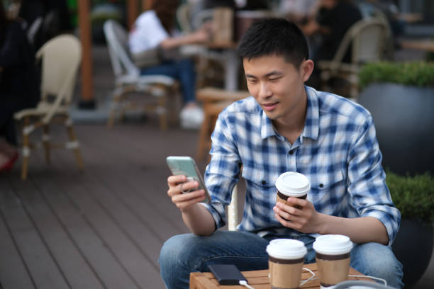 istock close up one young Asian man using phone at outdoor cafe. 1225316931