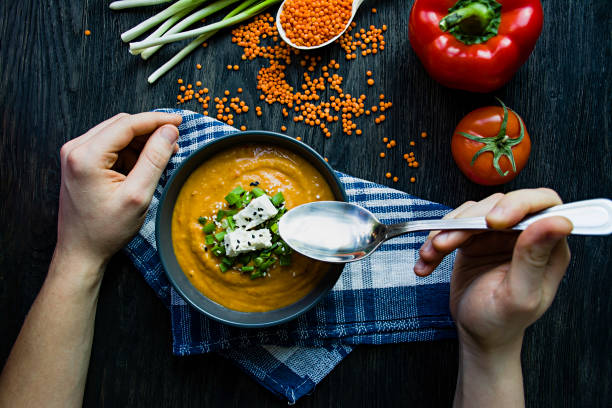 istock Red lentil cream soup decorated with fresh vegetables and herbs. A man eats soup. Veggie concept. Proper nutrition. 1225320652