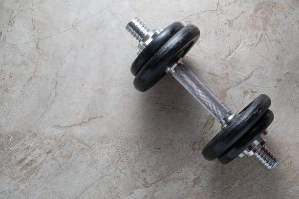 istock Dumbbells for muscle building exercise placed on cement floor with copyspace.Body workout in the gym training concept.new normal popular lifestyles for strong and healthy bodybuilding at home 1225320845