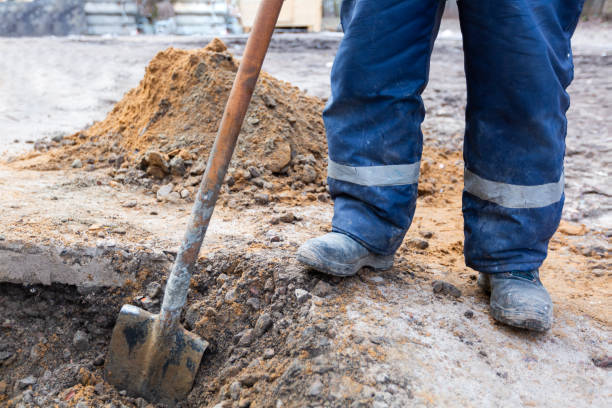 istock Worker in dirty uniform and shoes with shovel is digging a pit on construction site. Concept of hard work during construction, remodeling, renovation, extension, overhaul, restoration and reconstruction. 1225323530