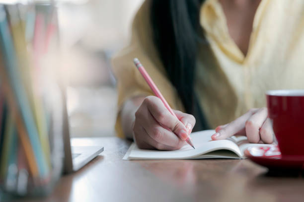 istock Closeup view of woman hand writing on notebook while working at home. 1225326518