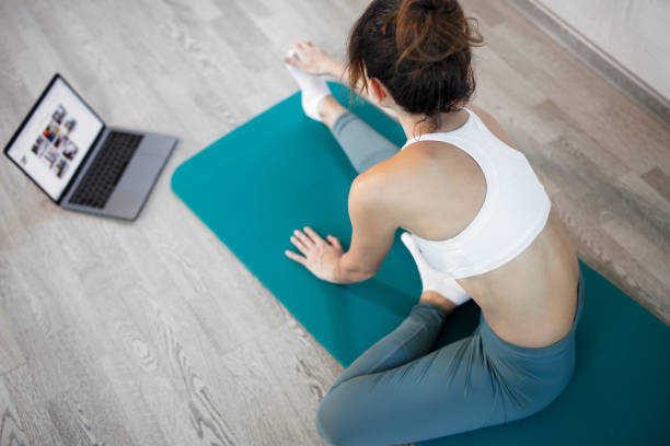 istock Young slim woman at home training. Workout online with a laptop. Stretching training. Online sport lessons. 1225326543