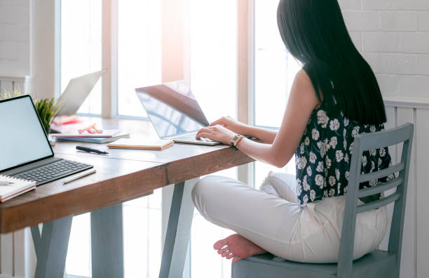 istock Young woman in casual wear working on laptop computer while sitting at home. 1225327802