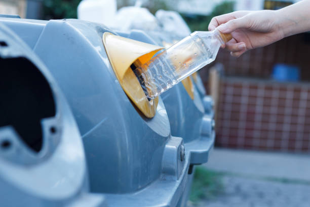 istock Closeup woman hand throwing empty plastic bottle in recycling bin. isolated outdoors background. 1225328454