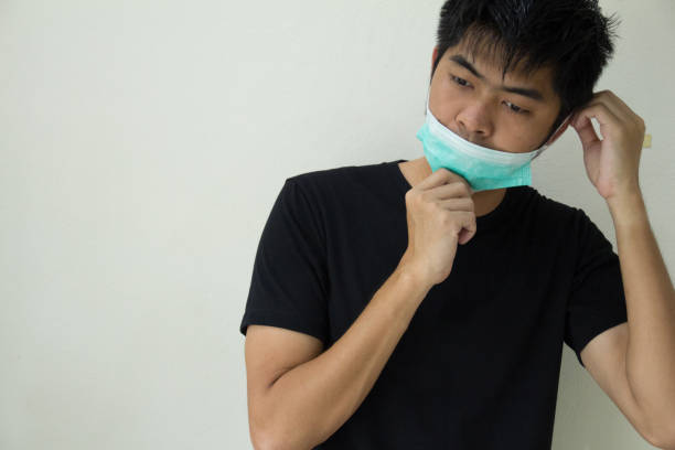 istock Young man feeling unwell and wearing face mask 1225328647
