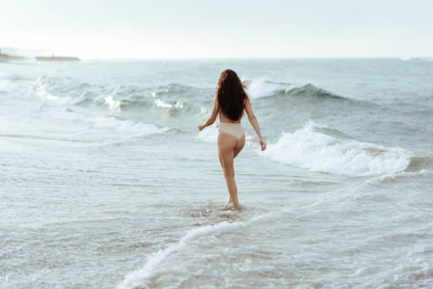 istock woman in bikini posing behind blue ocean 1225328652