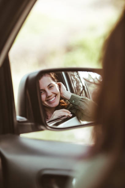 istock reflection on stunning smiling woman in car rear mirror 1225330077