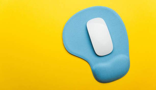 Top view flat lay of blue pad or mousepad with wireless white computer mouse modern design isolated on a yellow background and copy space Top view flat lay of blue pad or mousepad with wireless white computer mouse modern design isolated on a yellow background and copy space ergonomics-mouse stock pictures, royalty-free photos & images