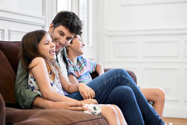 istock Man sitting with cheerful children watching TV 1225340877
