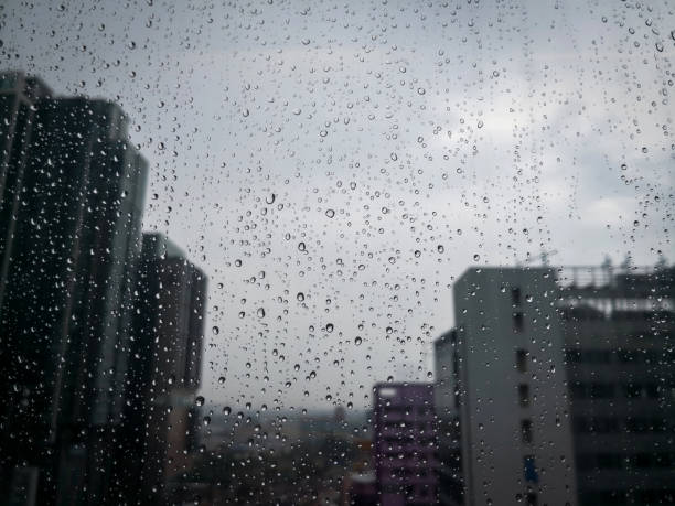 istock Rain drops on window glass with blurred skyscraper building in the city. 1225342423