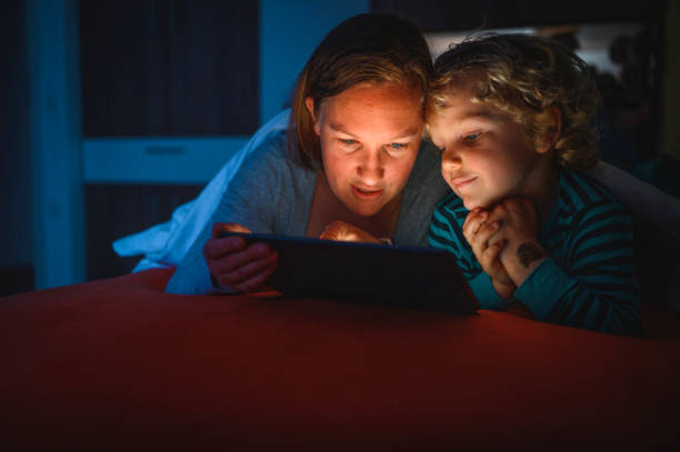 istock Cute blond boy and his mother using digital tablet at bedtime 1225348426