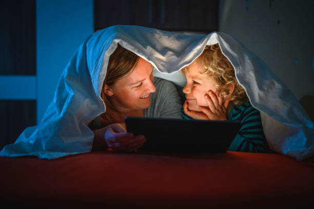 istock Cute blond boy and his mother using digital tablet at bedtime 1225348432