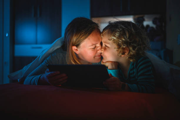istock Cute blond boy and his mother using digital tablet at bedtime 1225348435