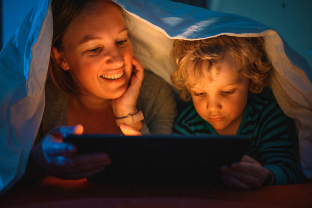istock Cute blond boy and his mother using digital tablet at bedtime 1225348439