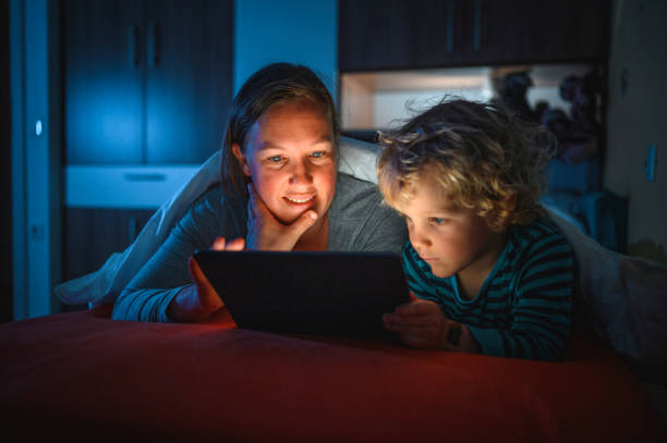 istock Cute blond boy and his mother using digital tablet at bedtime 1225348441