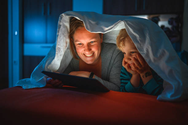 istock Cute blond boy and his mother using digital tablet at bedtime 1225348446