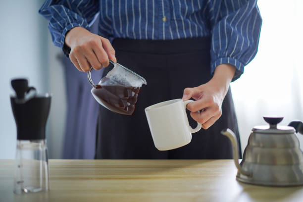 istock Young woman pouring brewed coffee into white mug 1225350168