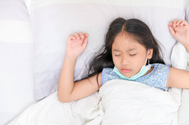 istock Asian girl wearing protective masks sleep on bed, 1225350196