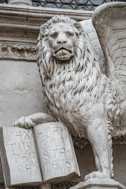 Photo of Winged lion with a Bible and a priest at Basilica San Marco in Venice, Italy, summer time, details, closeup
